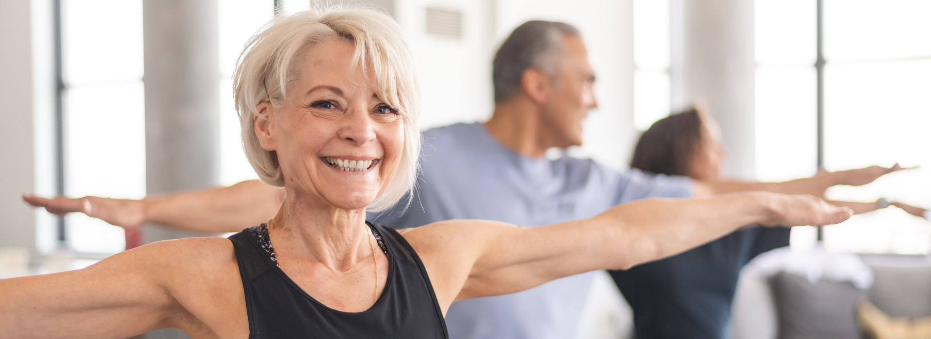 Senior Fitness Yoga Class | senior woman with arms outstretched smiling at the camera while doing a yoga class