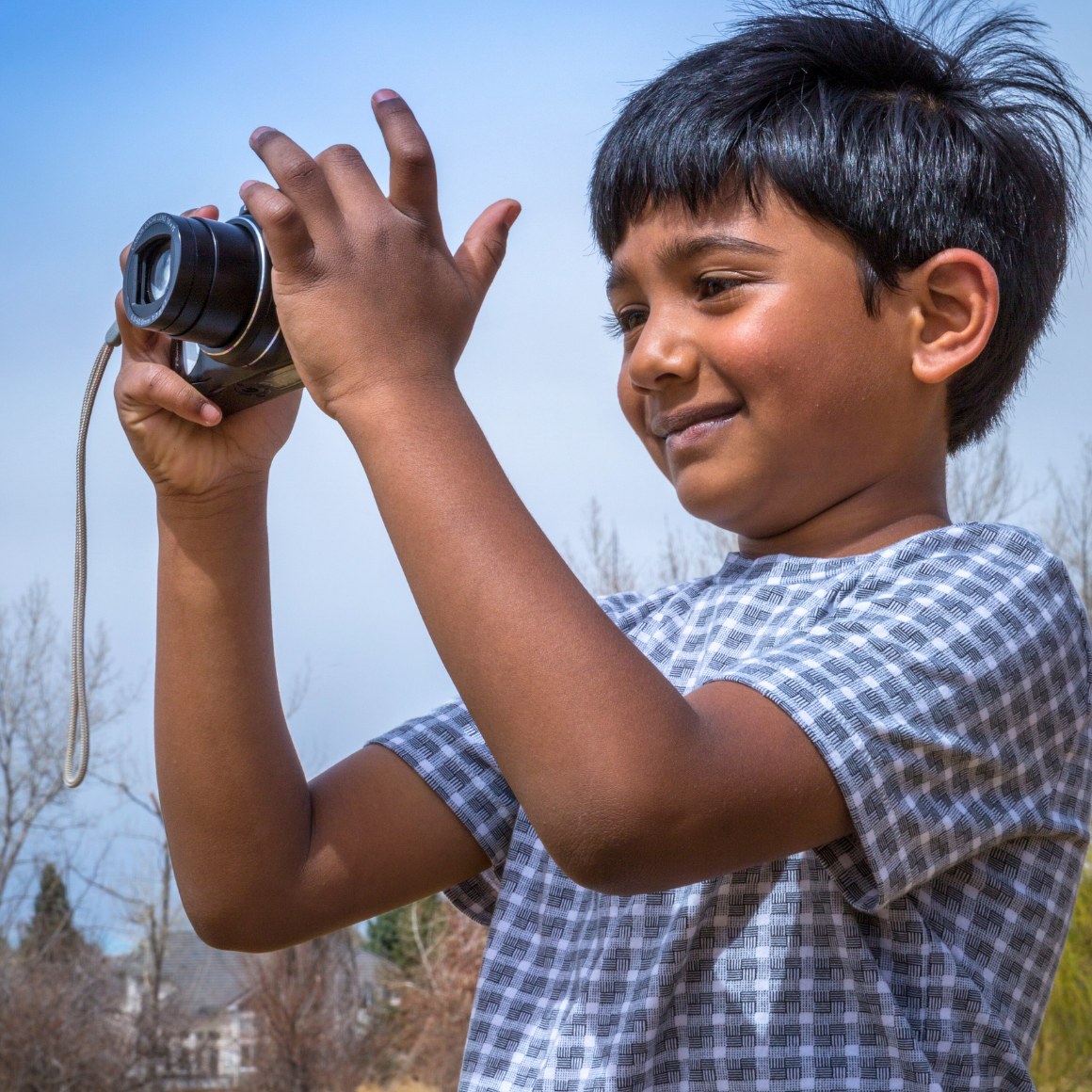 Photography Classes for Kids | Boy holding a camera up to his face and taking a picture.