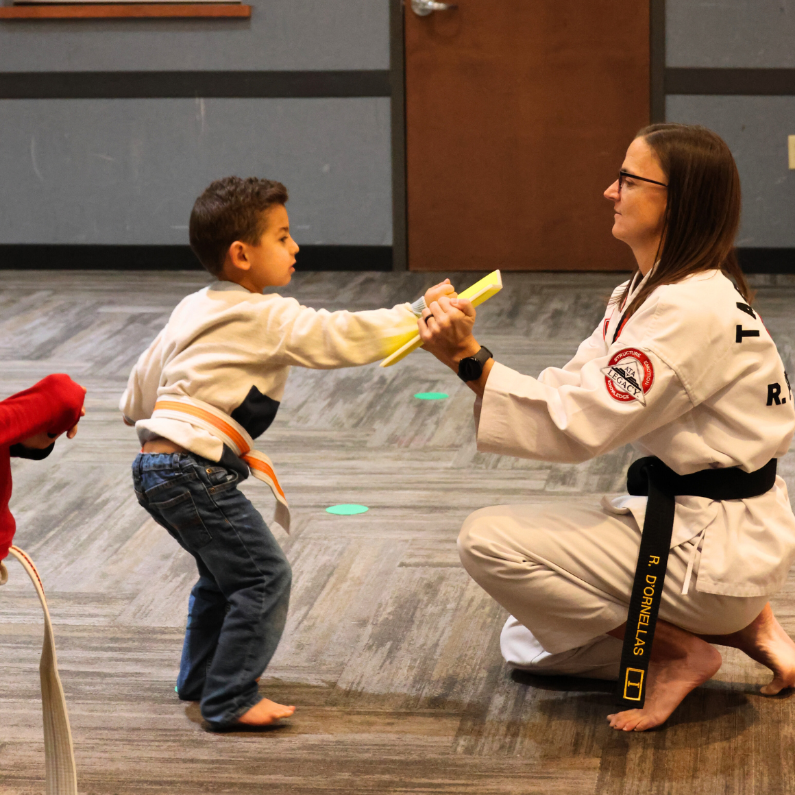 Taekwondo Martial Arts Class | Young boy hitting a board the instructor is holding