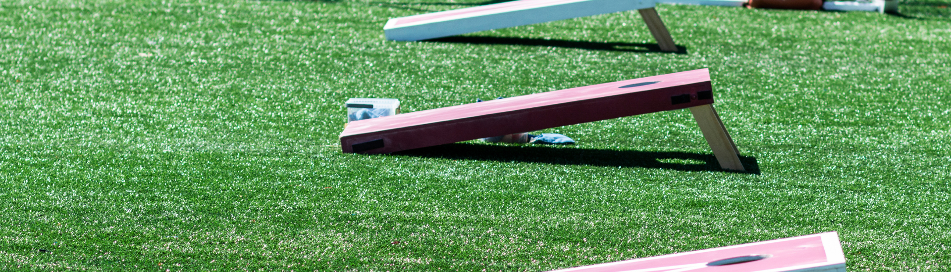 Trails Cornhole Tournament | 3 cornhole boards with bean bags on artificial turf