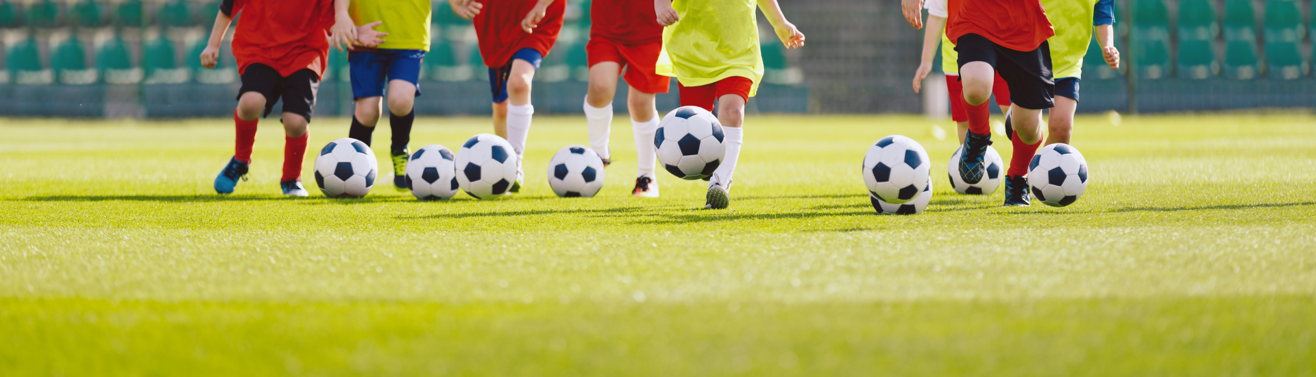 Youth Sports Website Header | a shot of 8 young kids kicking a soccer ball on a soccer field