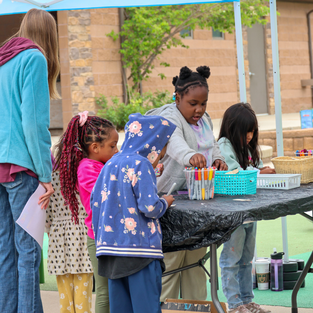 Summer Celebration 2024 | A group of 4 kids coloring from a distance at Arapahoe Libraries tent