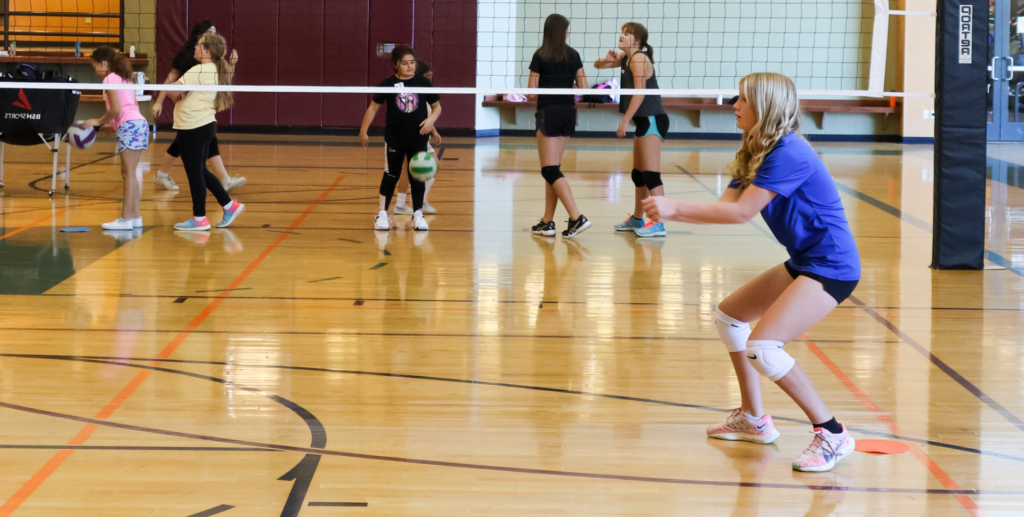 Volleyball Program Blog | a young girl in front of a volleyball net preparing to hit a volleyball